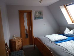 Schlafzimmer mit Doppelbett und Nachtkonsolen. Tür geht ins Ankleidezimmer